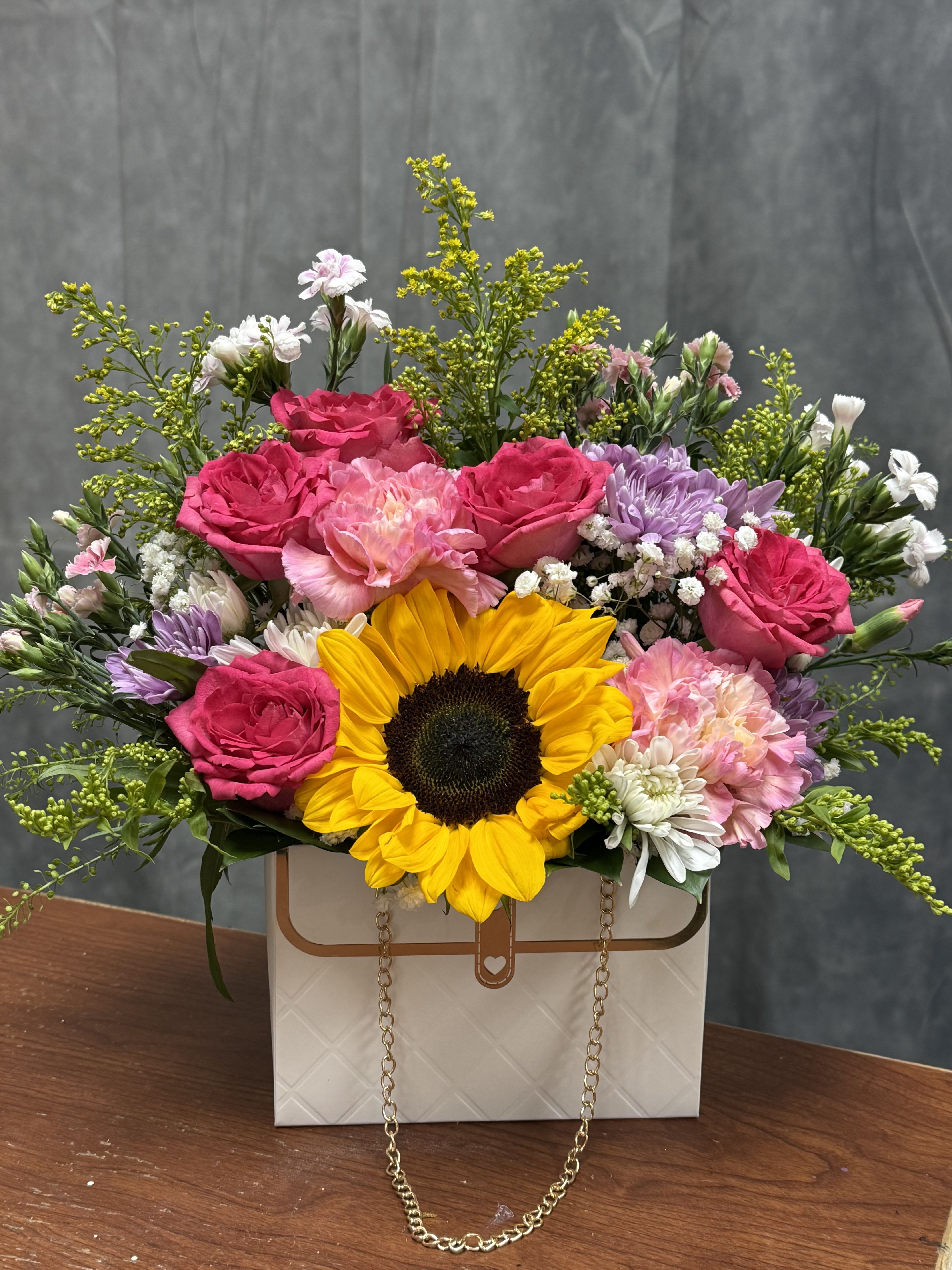 Mixed bouquet with a sunflower, pink roses, and pastel flowers in a gift box