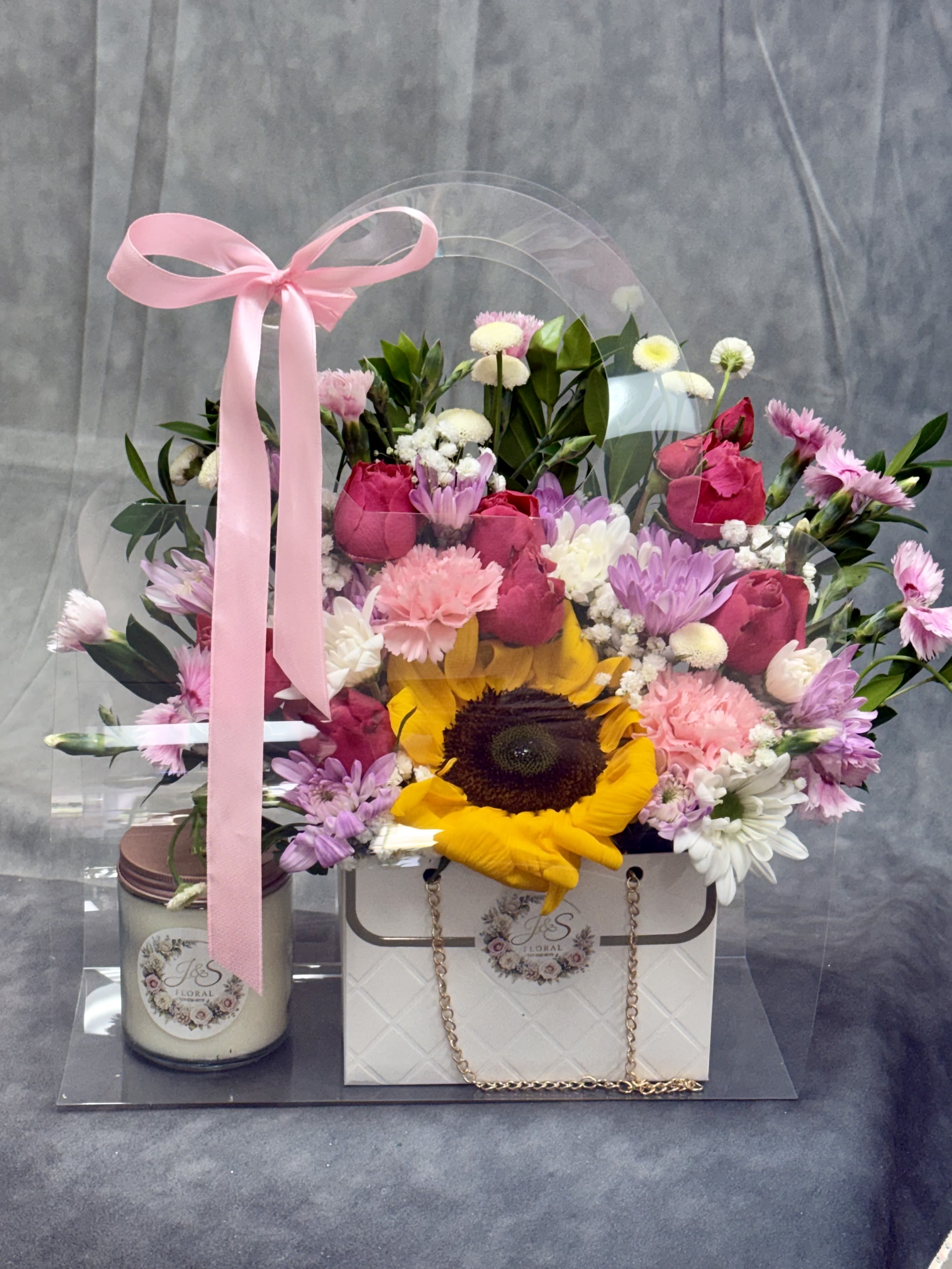 Cheerful Sweet Flames Bag - Introducing our cheerful Sweet Flames Bag — a heartwarming trio featuring a charming floral purse arrangement, decadent chocolates, and a soothing scented candle. The perfect gift to spark joy and sweeten someone’s day! The candle scent may be changed depending on the availability. 