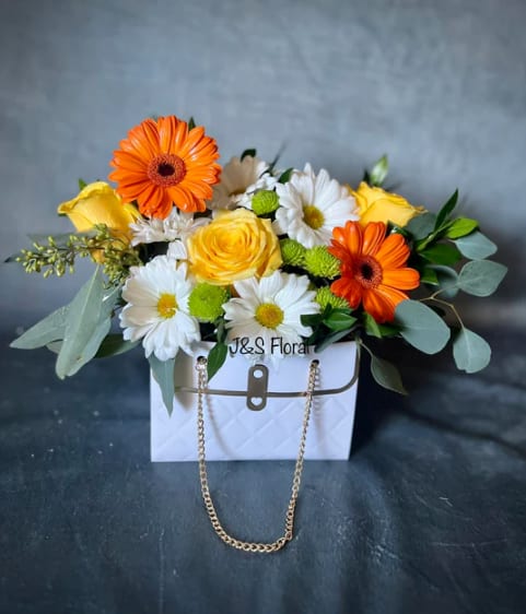 Bouquet of orange and yellow flowers in a white handbag-style box