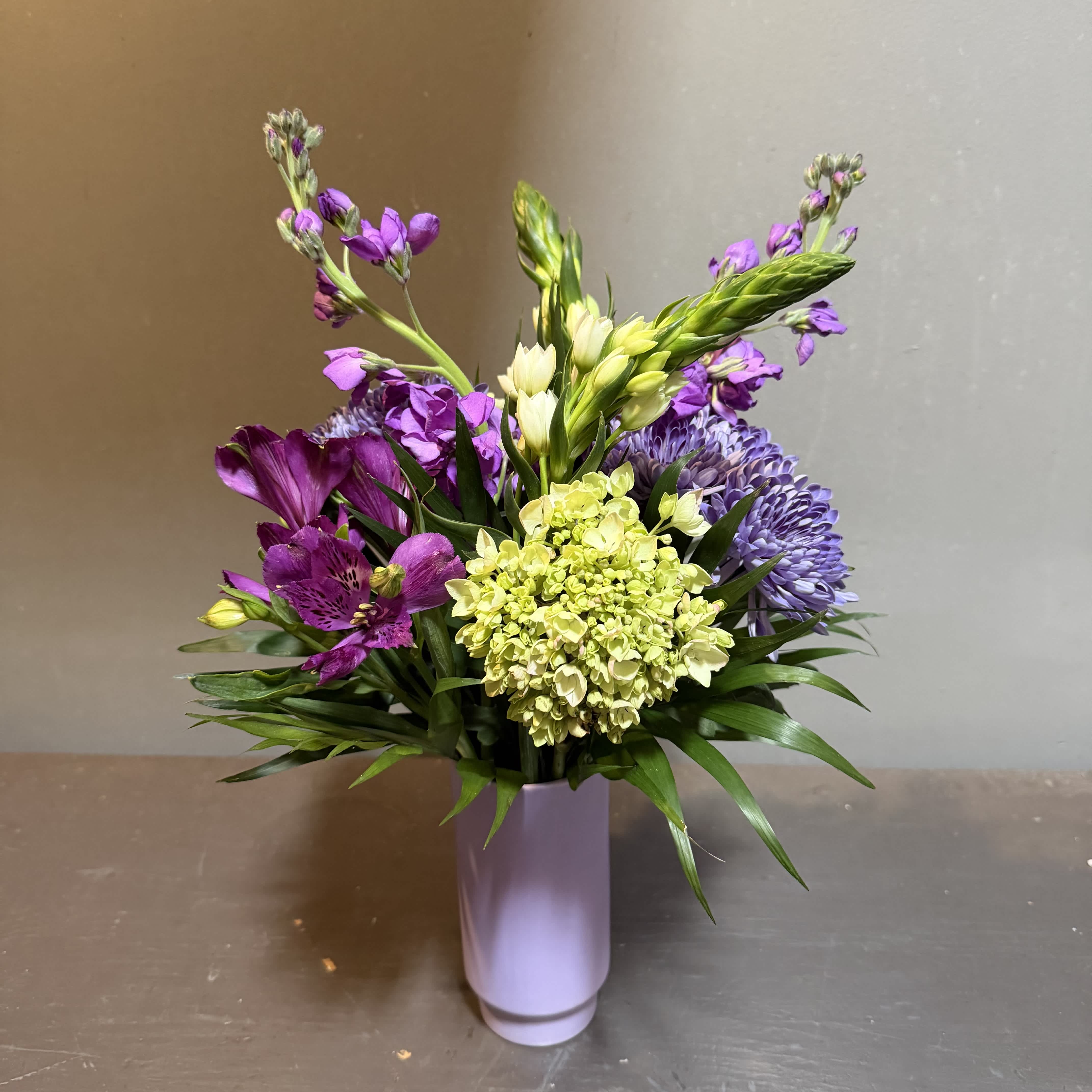 Purple and yellow mixed bouquet in a lavender vase
