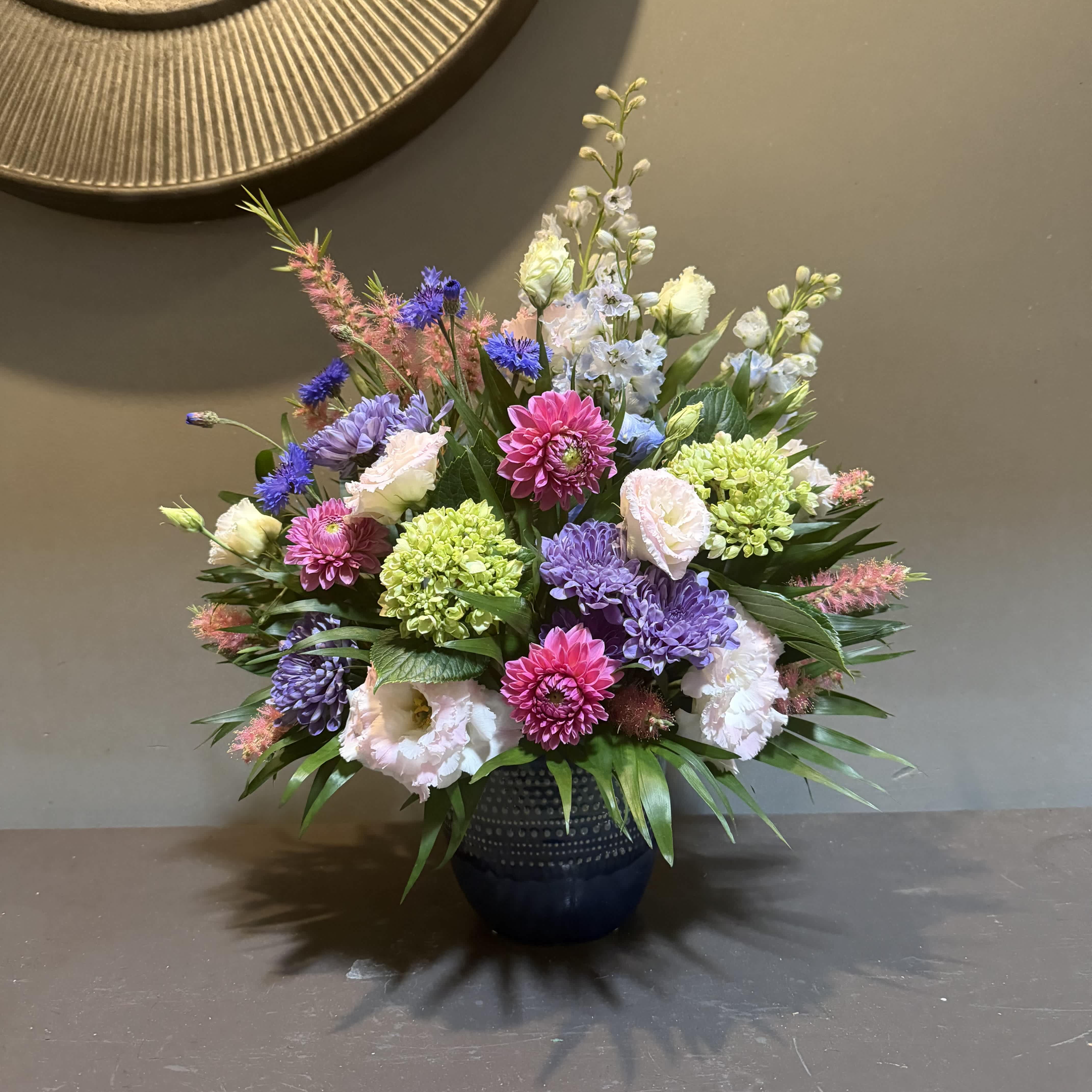 Mixed bouquet in a dark blue vase with pink, purple, white, and green blooms