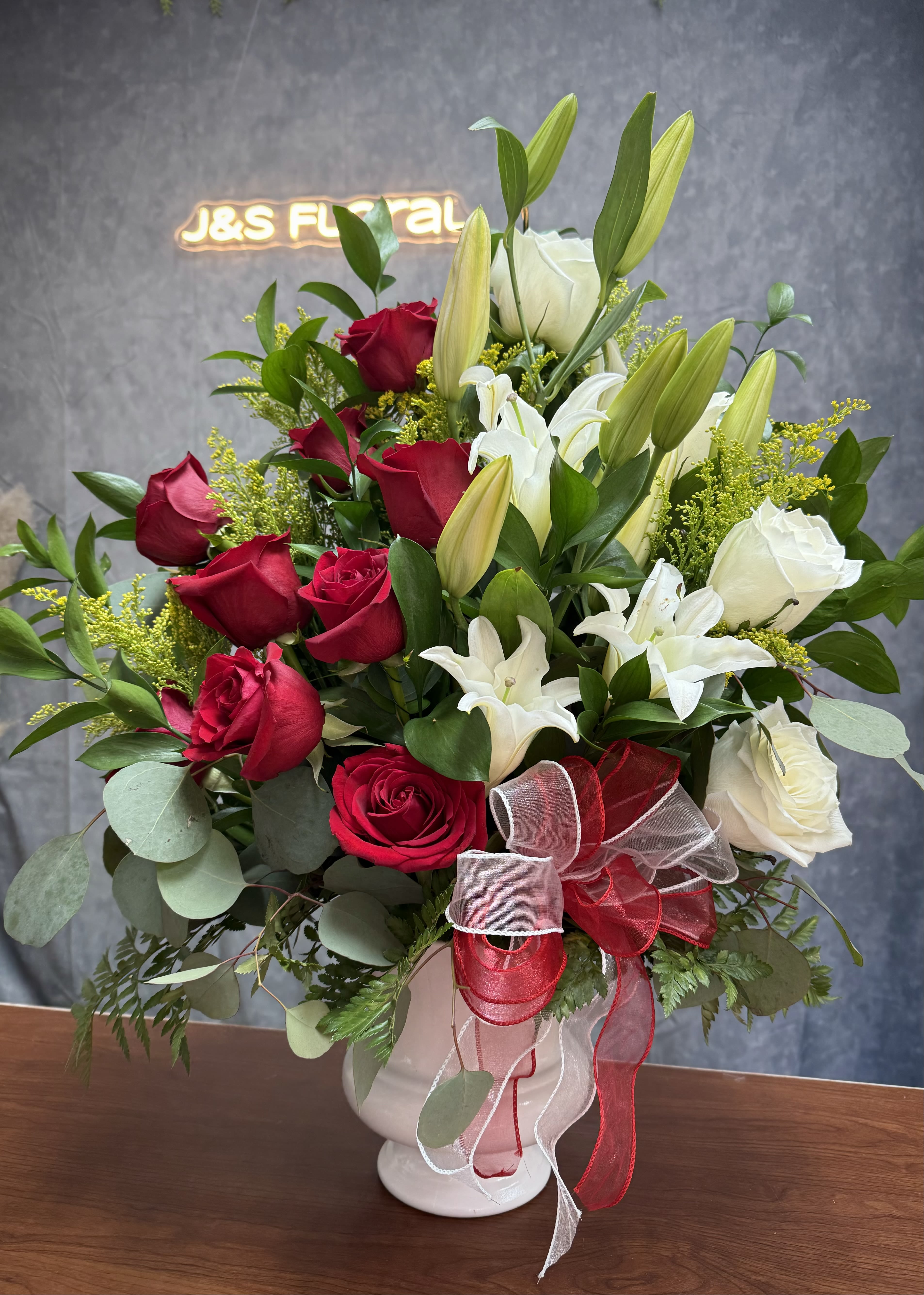 Bouquet of red and white roses with lilies in a white vase
