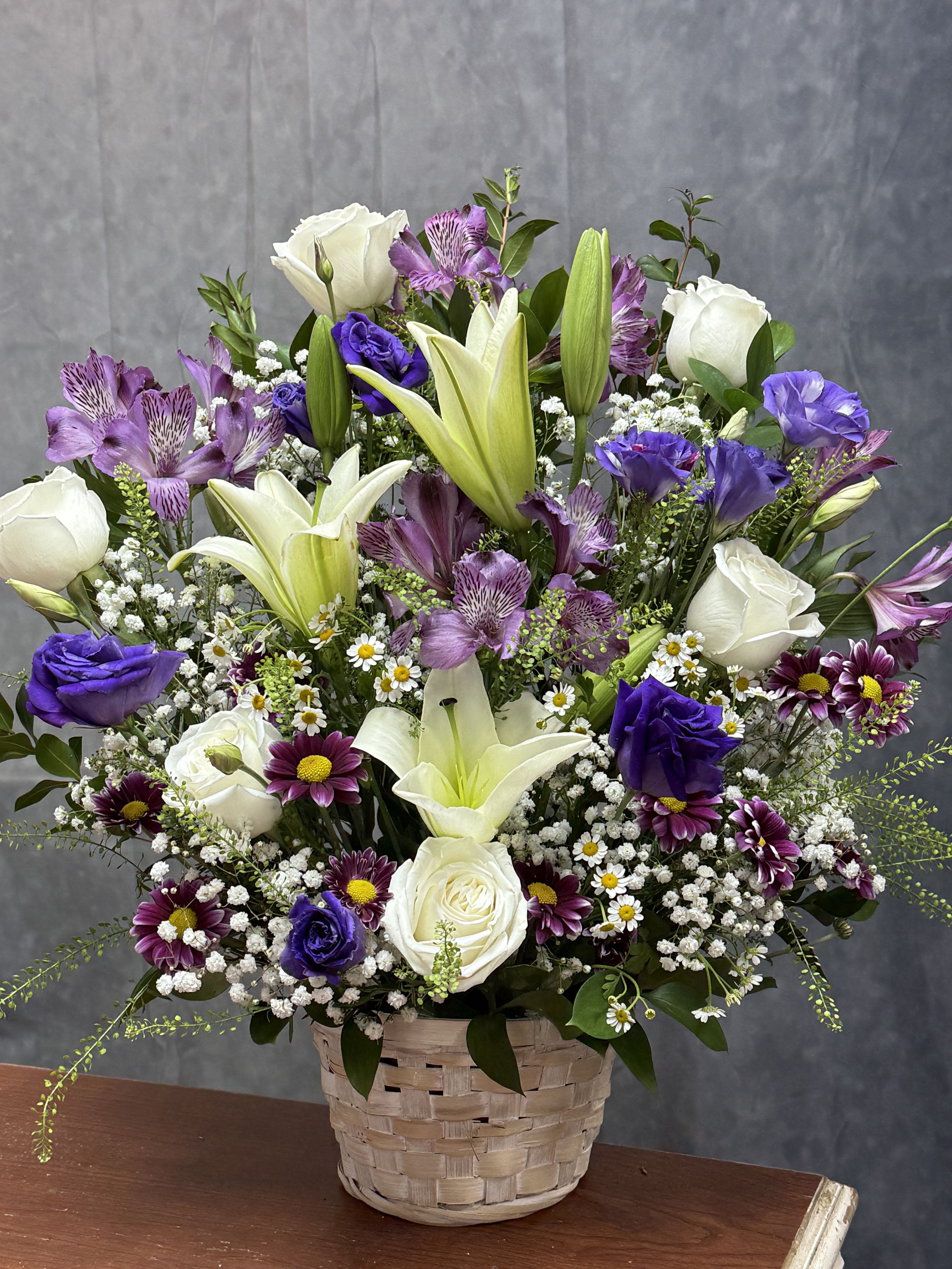 White Purple Basket  - Elegant and timeless, our White Purple Basket is a beautiful blend of white lilies, roses, Alstroemeria and carnations, arranged in a classic neutral basket. Perfect for expressing sympathy, love, or pure elegance, this arrangement brings a touch of grace to any space. 