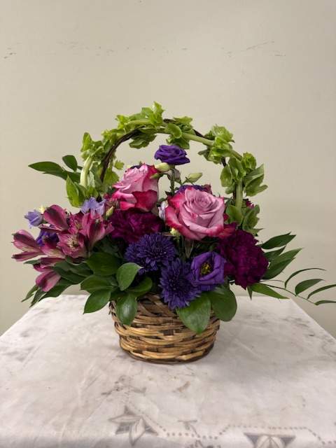 Basket arrangement of pink and purple flowers with greenery