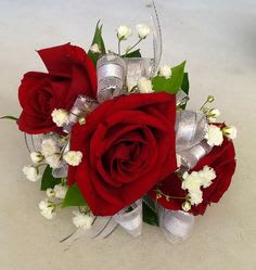 Red roses with white filler flowers and silver ribbon accents