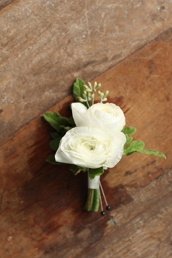 Small white flower boutonniere with green accents