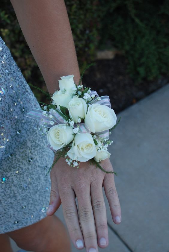 White rose wrist corsage with ribbon on a person's wrist