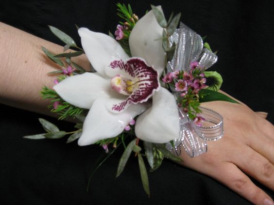 White orchid wrist corsage with silver ribbon on a wrist