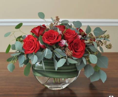 Red roses in a glass vase with eucalyptus