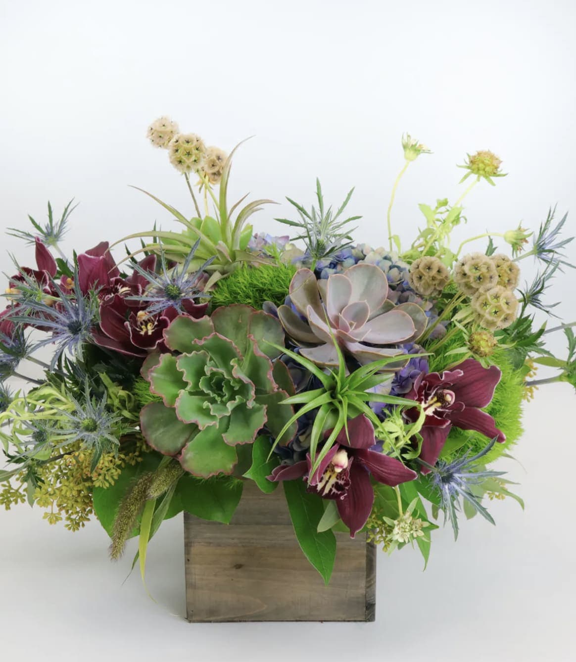Succulent arrangement with burgundy orchids in a wooden box