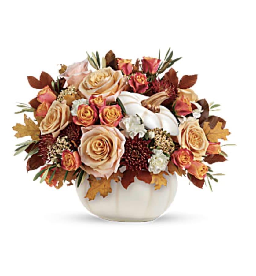 Autumn bouquet of peach and pink roses in a white pumpkin vase