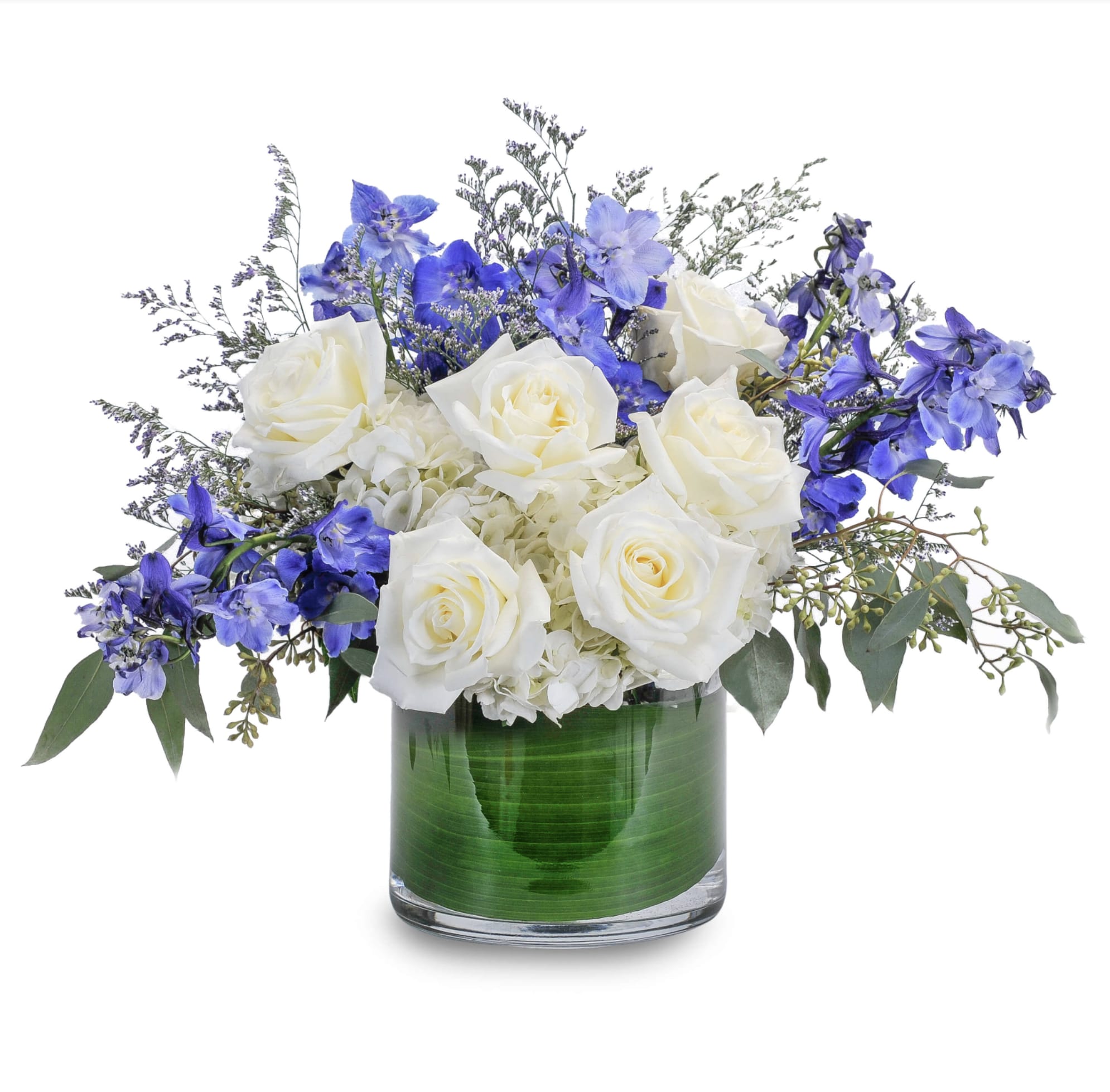 White roses and blue flowers arranged in a glass vase