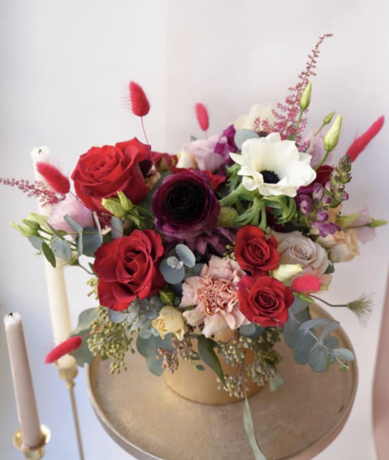 Mixed bouquet of red, white, and pink flowers in a gold vase