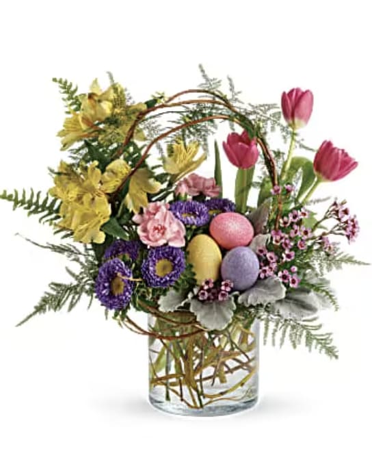 Colorful spring bouquet in a clear glass vase with decorative eggs