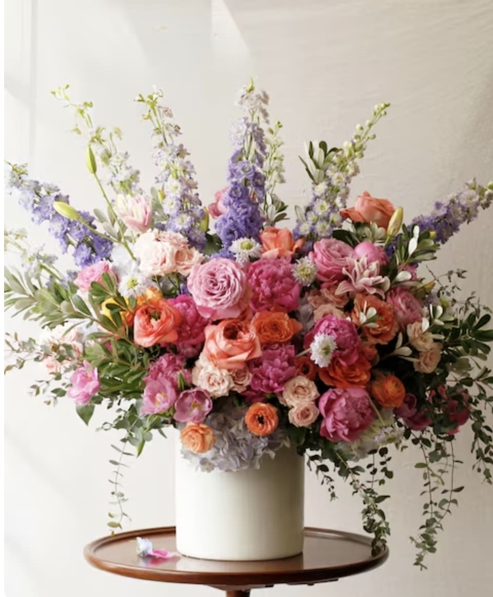 Large mixed bouquet in a white vase with pink, orange, and purple flowers