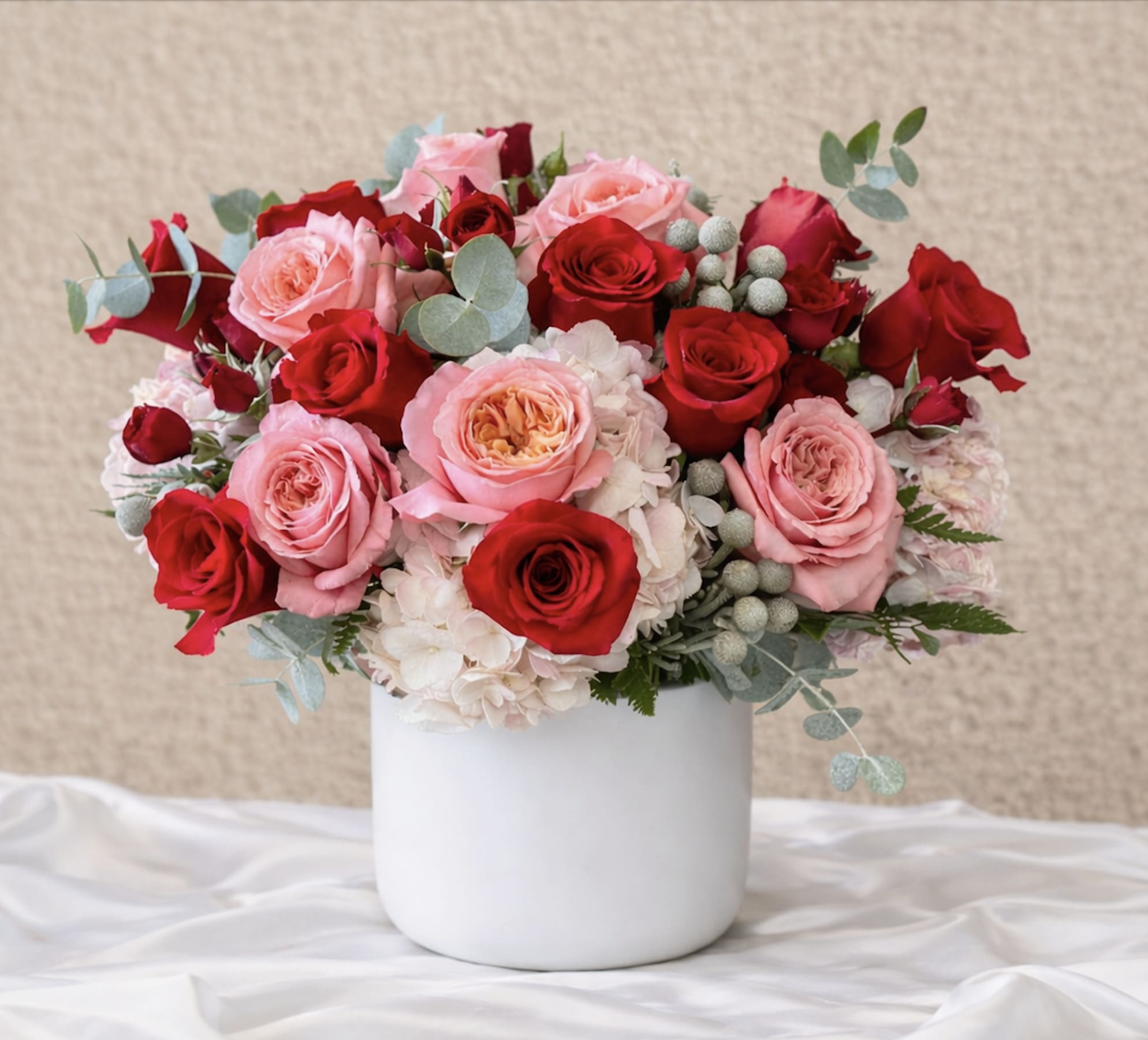 Pink and red roses arranged in a white vase