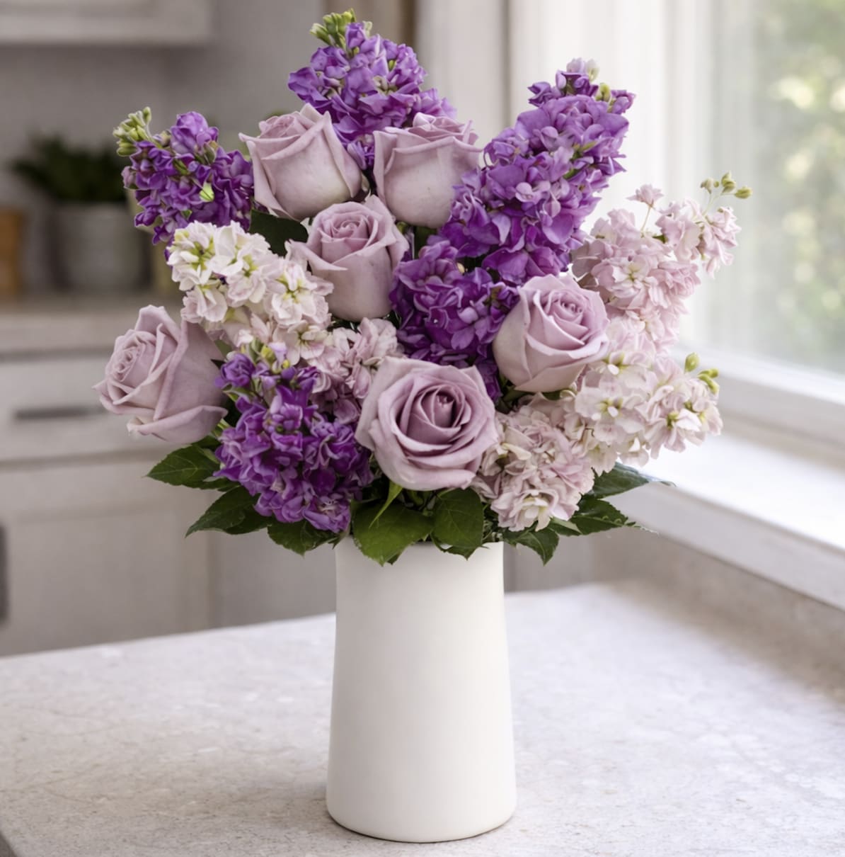 Lavender roses and purple flowers in a white vase
