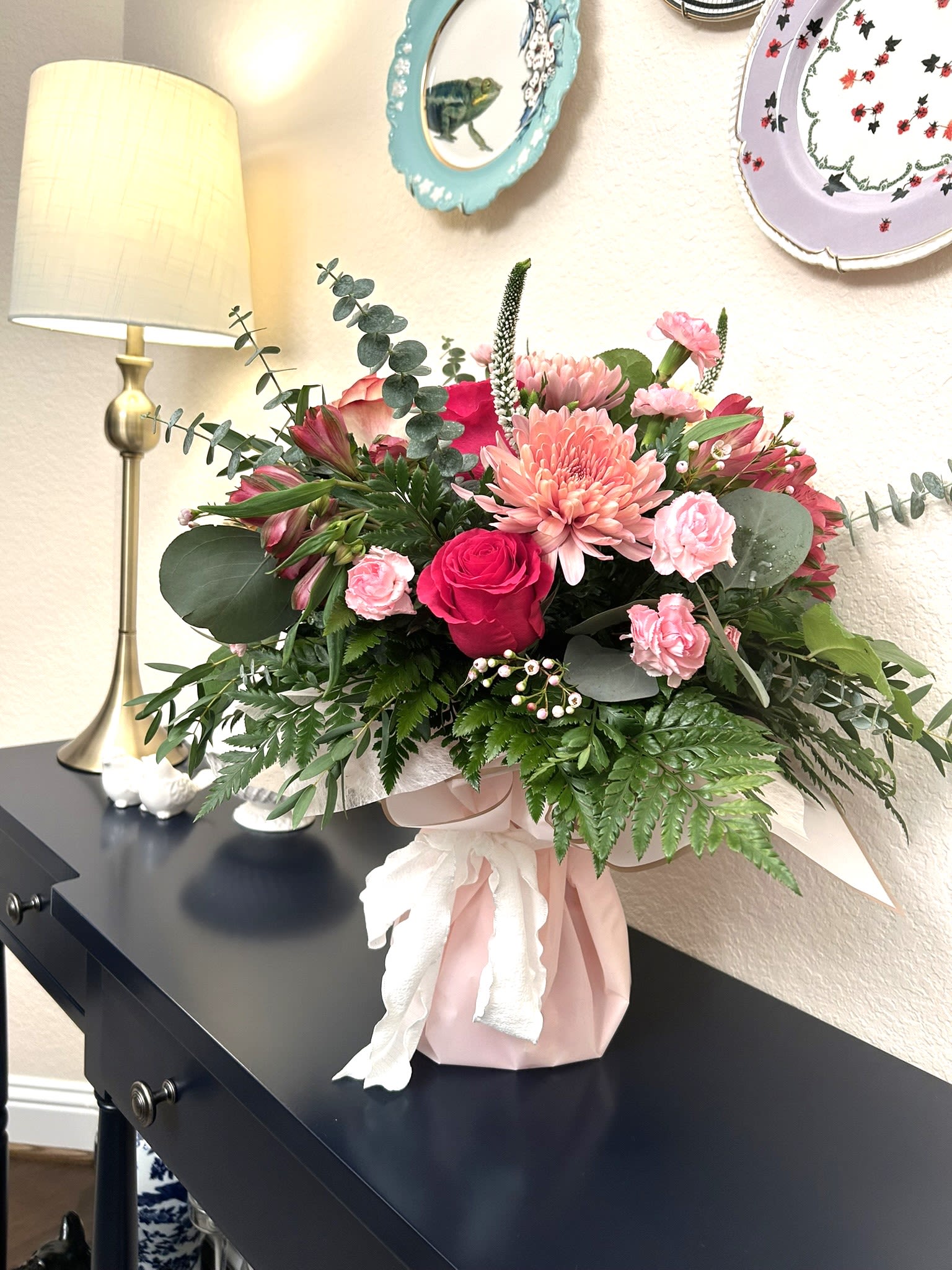 Pink and red mixed flower arrangement in a wrapped vase