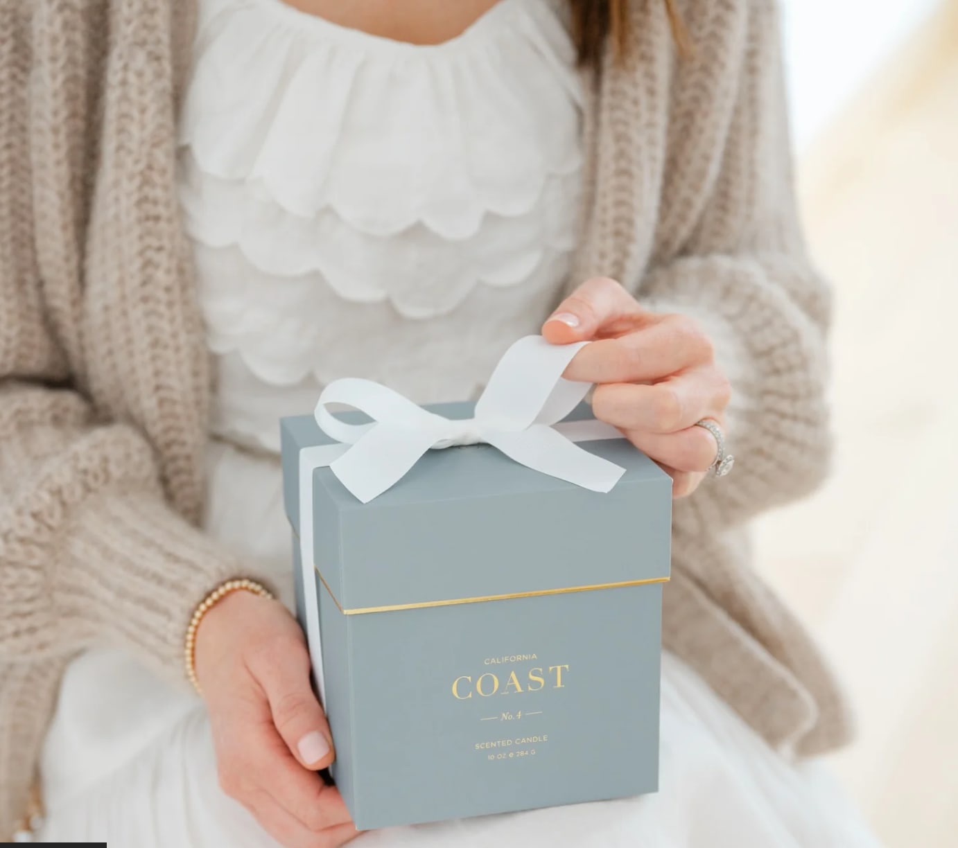Person holding a blue gift box with a white ribbon