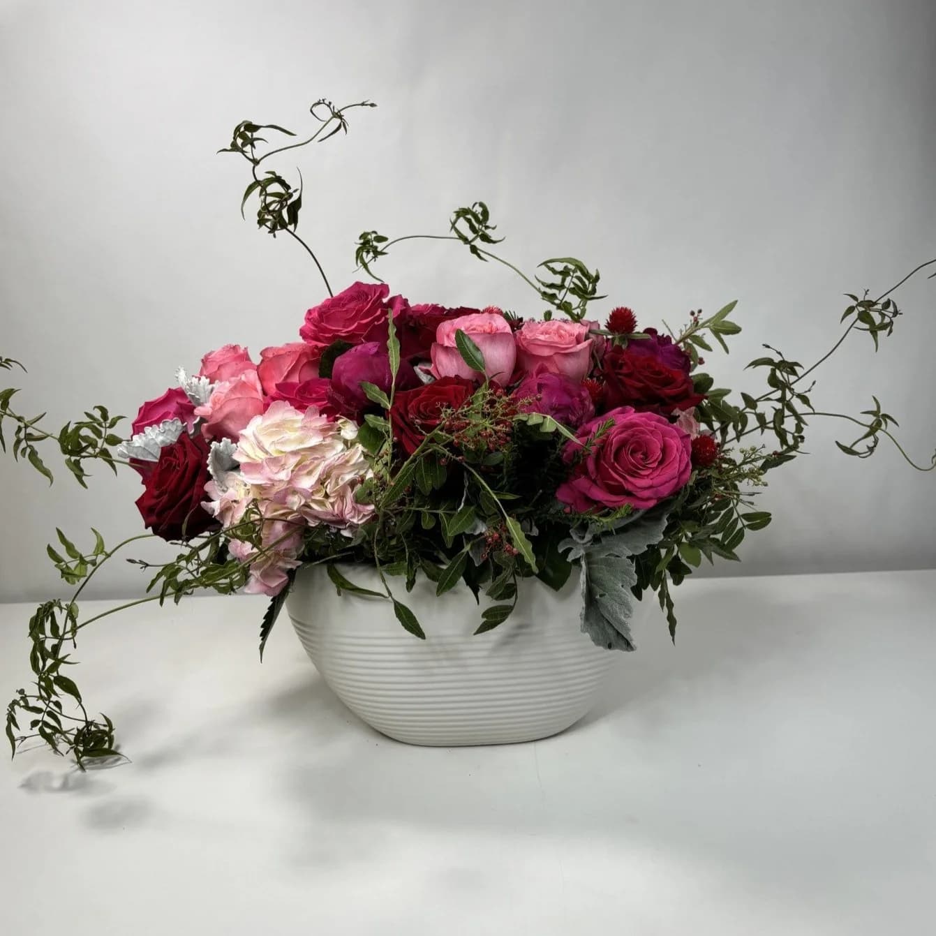 Mixed pink and red roses arranged in a white bowl vase
