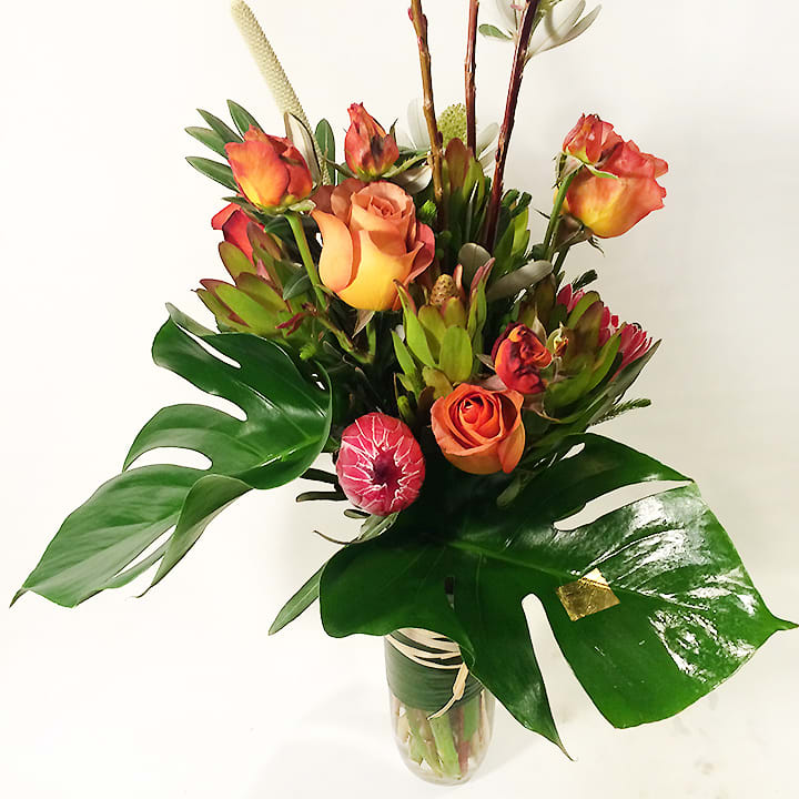 Tropical bouquet with orange roses in a glass vase