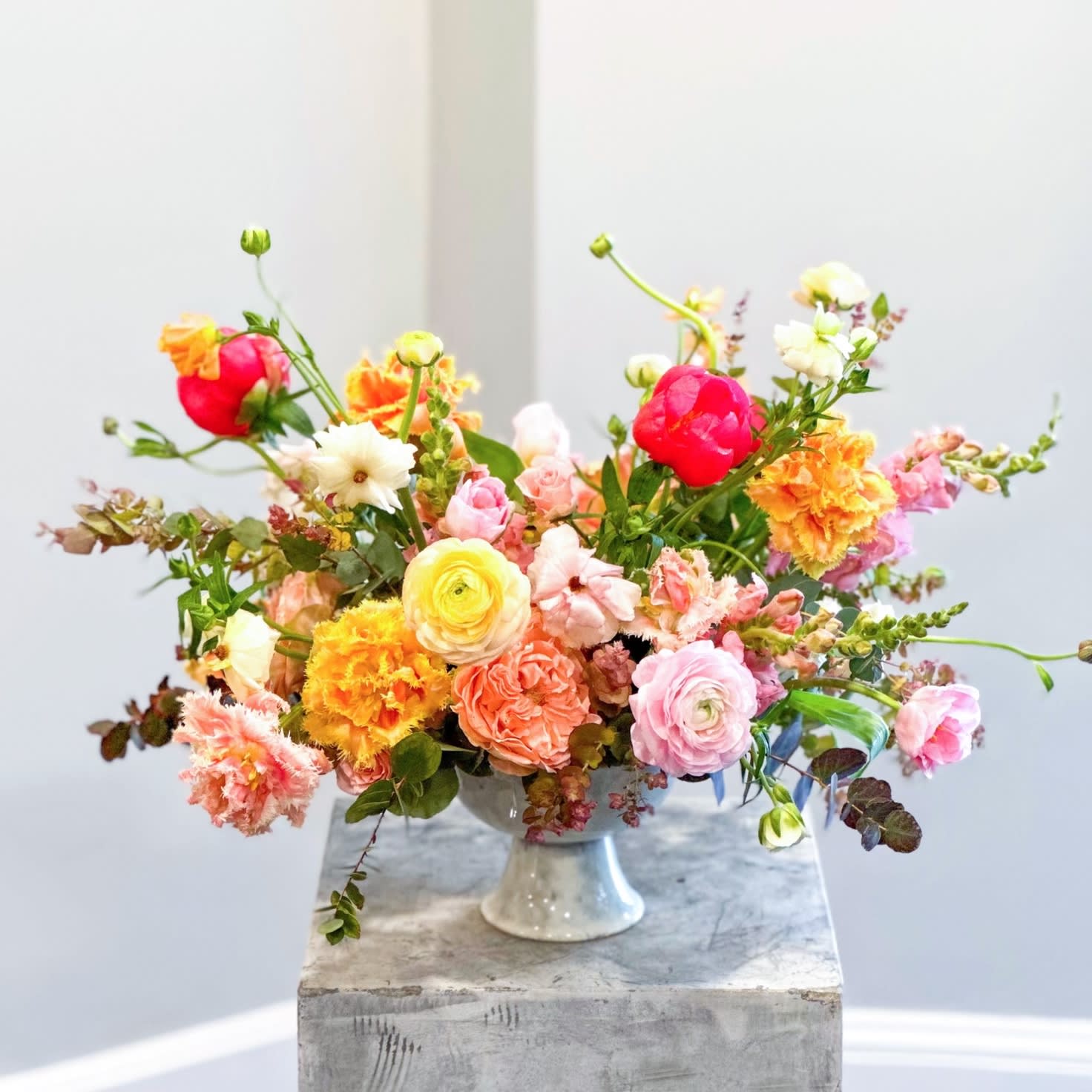Colorful mixed flower arrangement in a white pedestal vase
