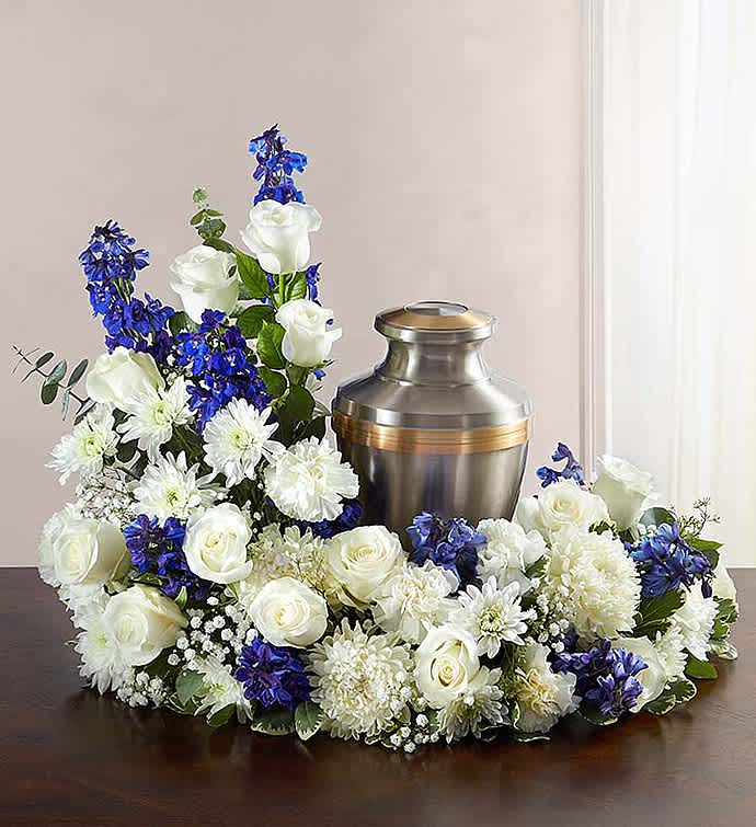 White and blue floral arrangement surrounding a metal urn