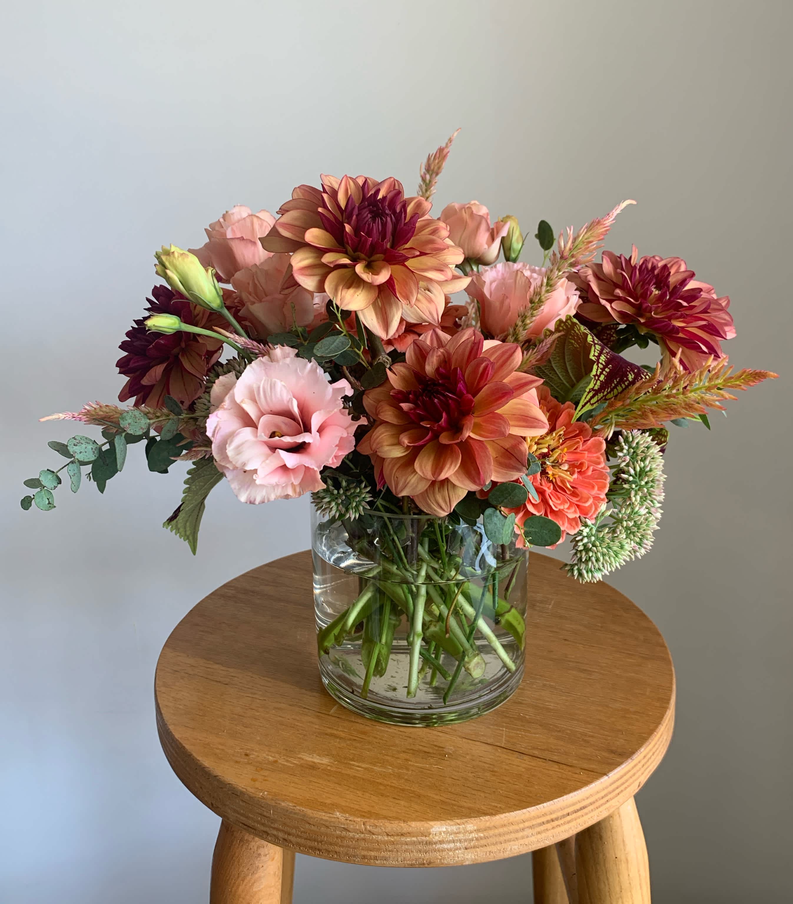 Mixed pink and peach flowers arranged in a clear glass vase