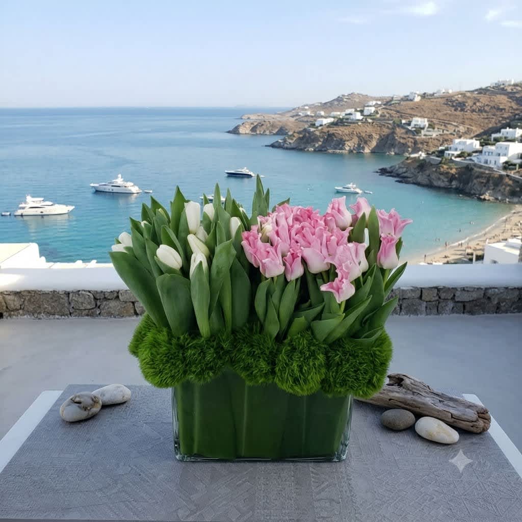 Pink and white tulips arranged in a glass vase with green moss accents