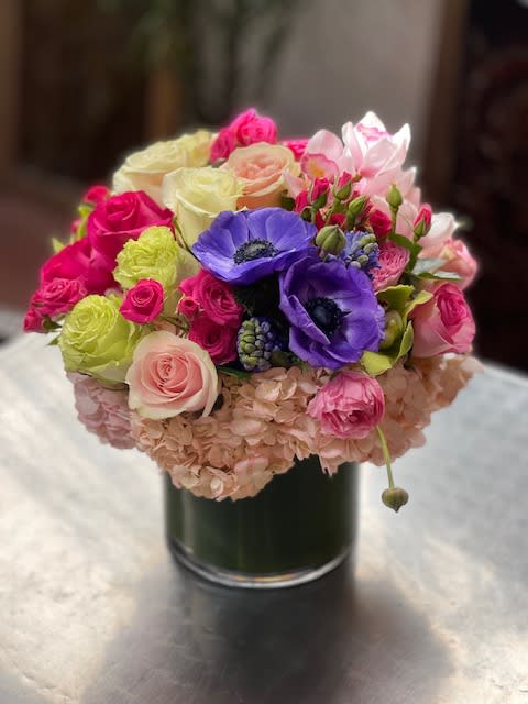 Colorful bouquet of roses, anemones, and hydrangeas in a glass vase