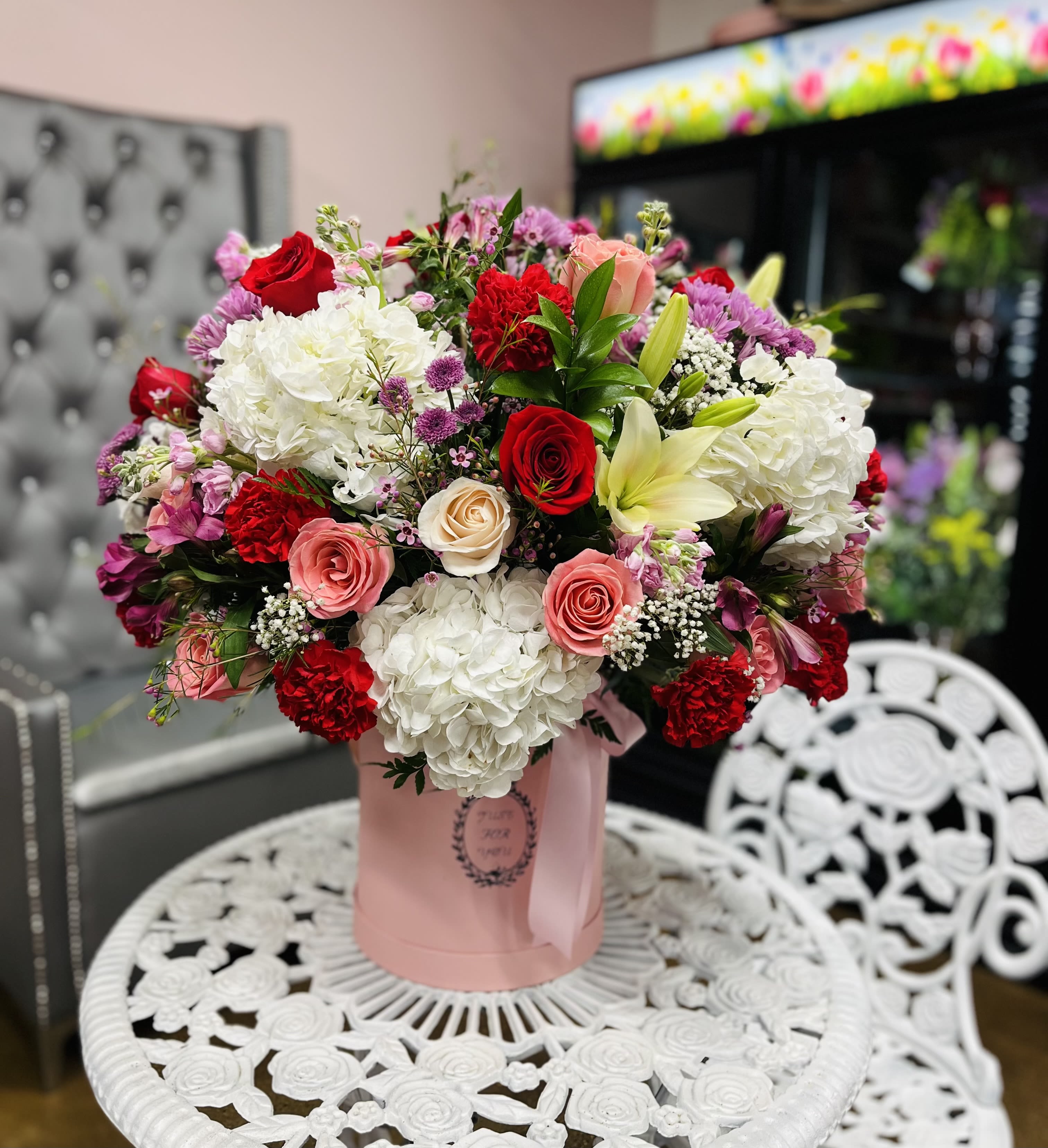 Bouquet of red, pink, and white flowers in a pink hatbox