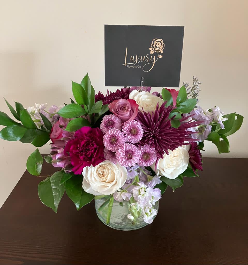 Pink, white, and purple flower arrangement in a clear glass vase