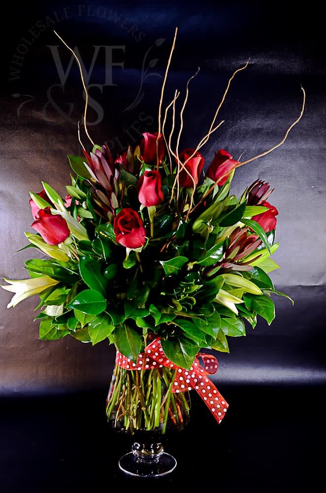 Red roses arranged in a clear glass vase with a polka-dot ribbon