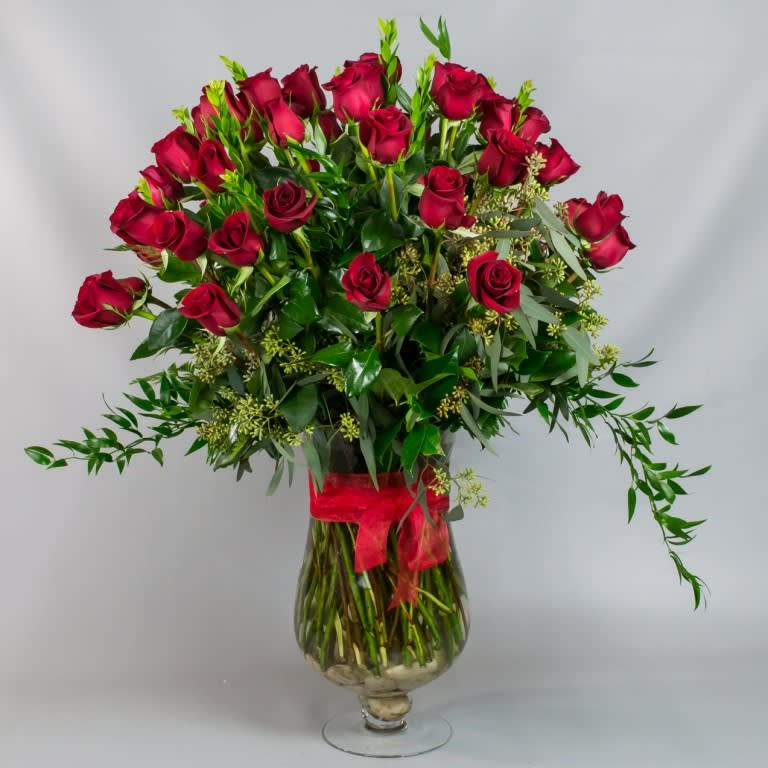 Bouquet of red roses in a clear glass vase with a red ribbon