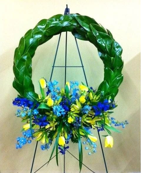 Blue and yellow floral wreath on a black easel