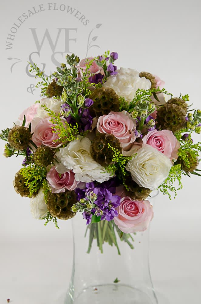 Pink and white roses with purple flowers in a clear glass vase