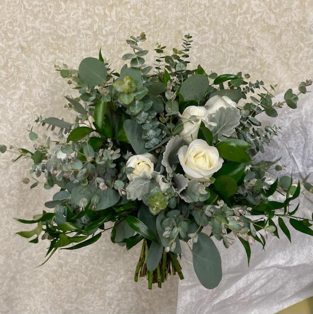 White roses and eucalyptus in a loose hand-tied bouquet