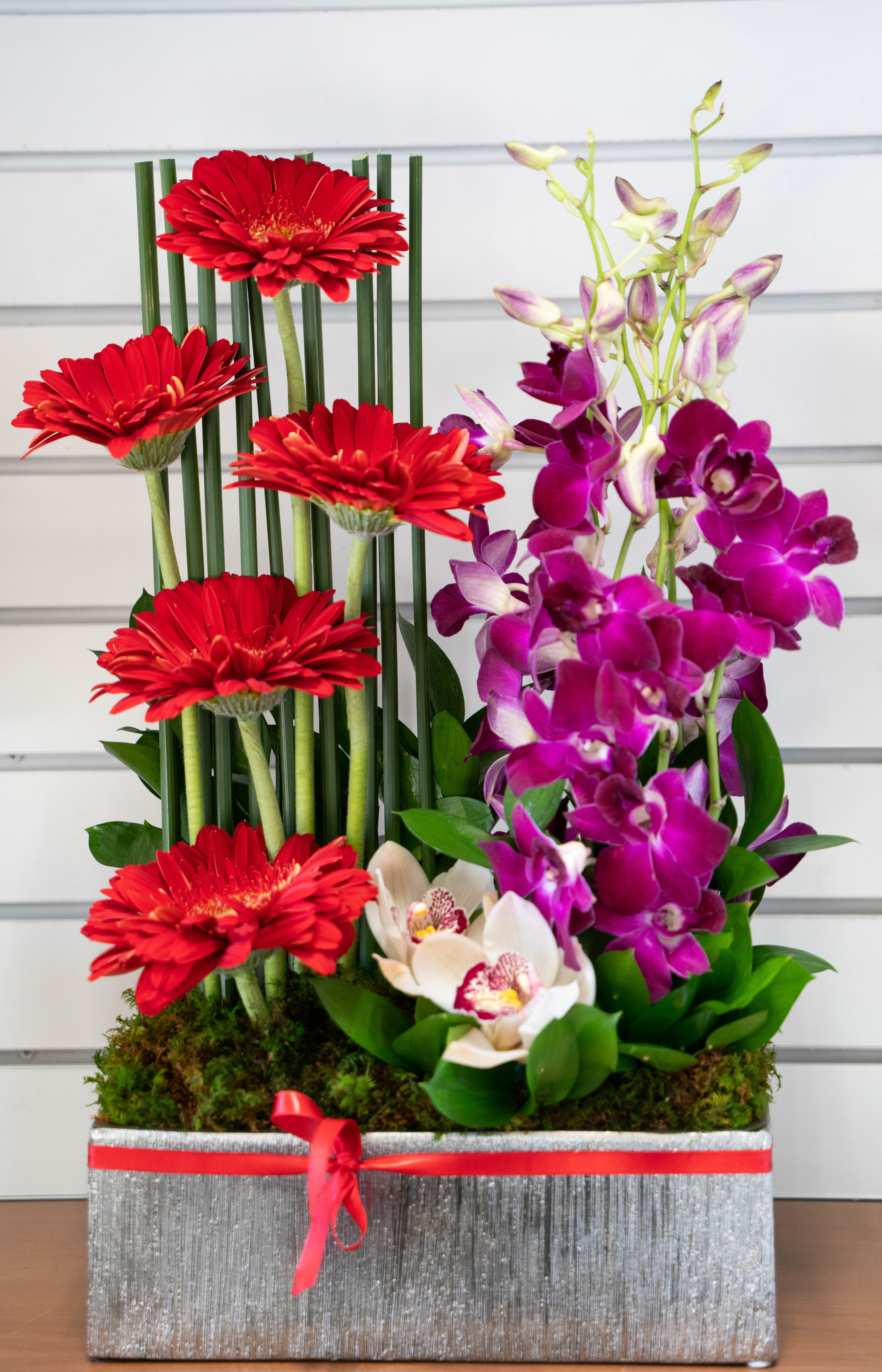 Red gerberas and purple orchids in a rectangular gift box