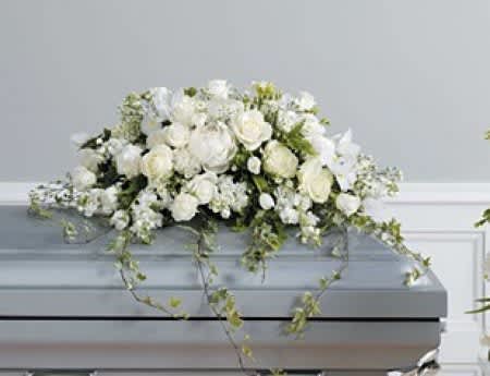 White floral casket spray with trailing greenery