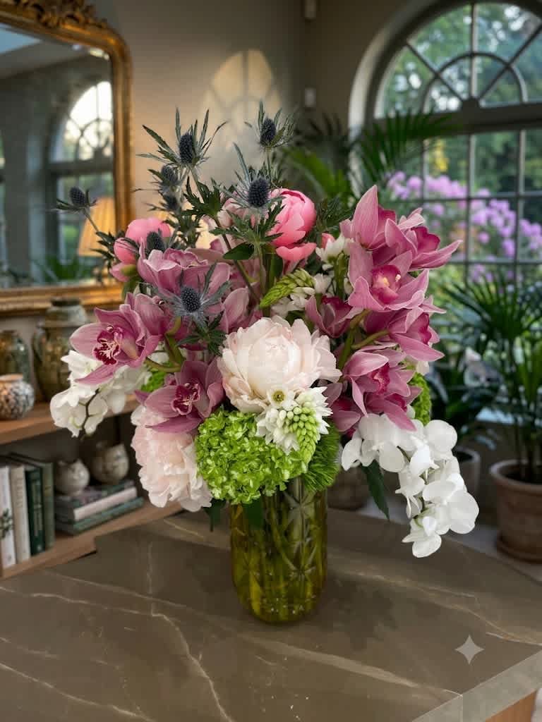 Pink and white orchid arrangement in a glass vase with green hydrangea