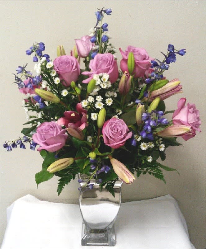 Pink roses and lilies arranged in a clear glass vase