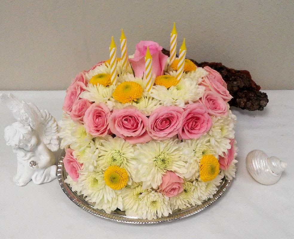 Pink roses and white daisies arranged as a cake with candles