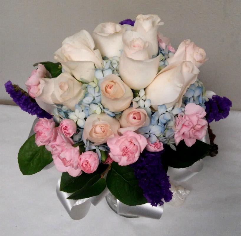 Bouquet of white roses, pink carnations, and blue hydrangeas with purple accents