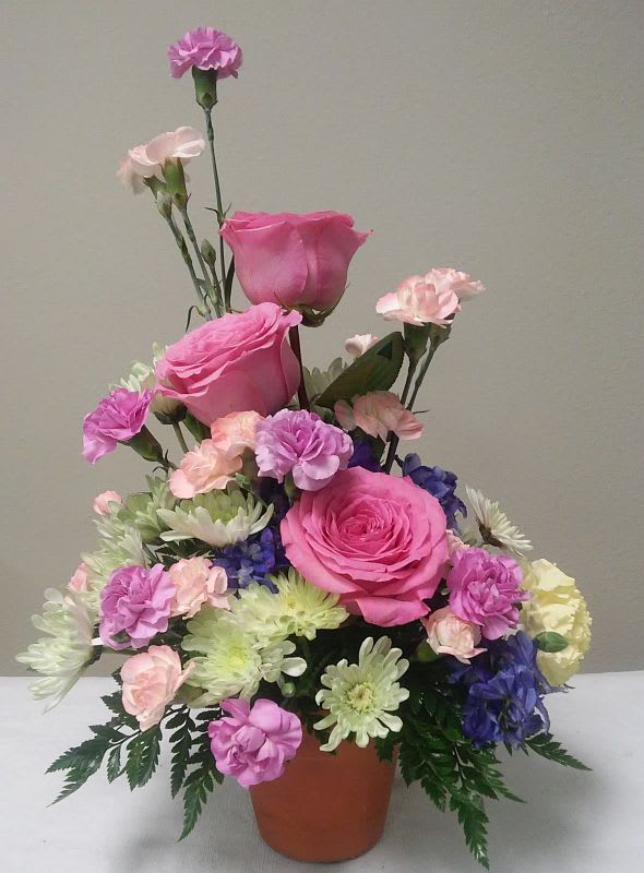 Pink roses and mixed carnations in a terracotta pot