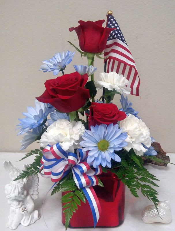 Red roses and blue-white daisies arranged with an American flag