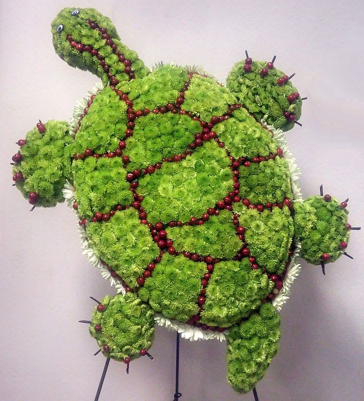 Turtle-shaped floral arrangement made of green blooms with red berry accents