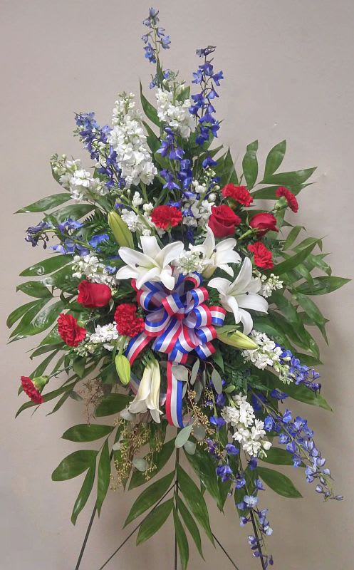 Standing floral spray with red roses, white lilies, and blue flowers