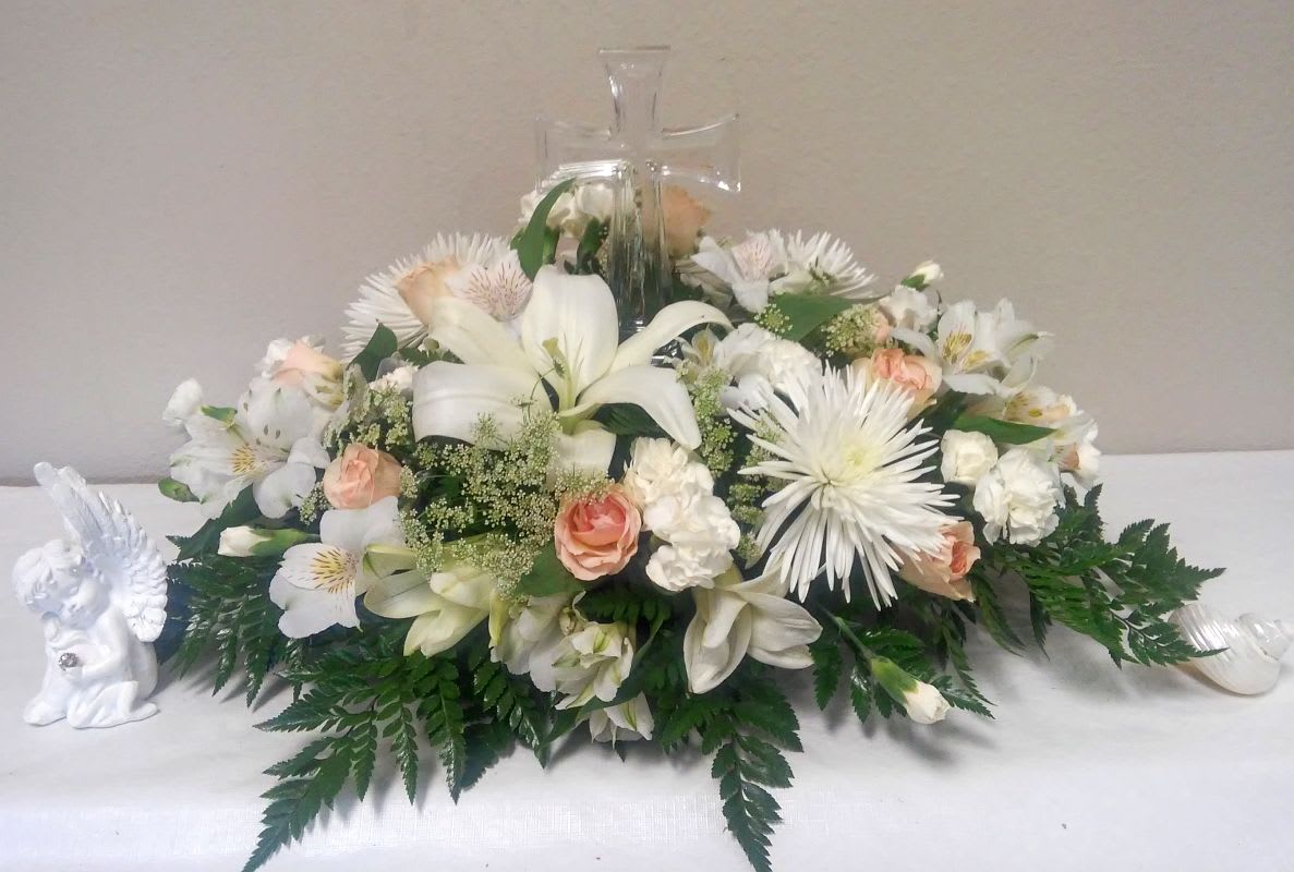 White floral arrangement with lilies and roses in a glass cross vase
