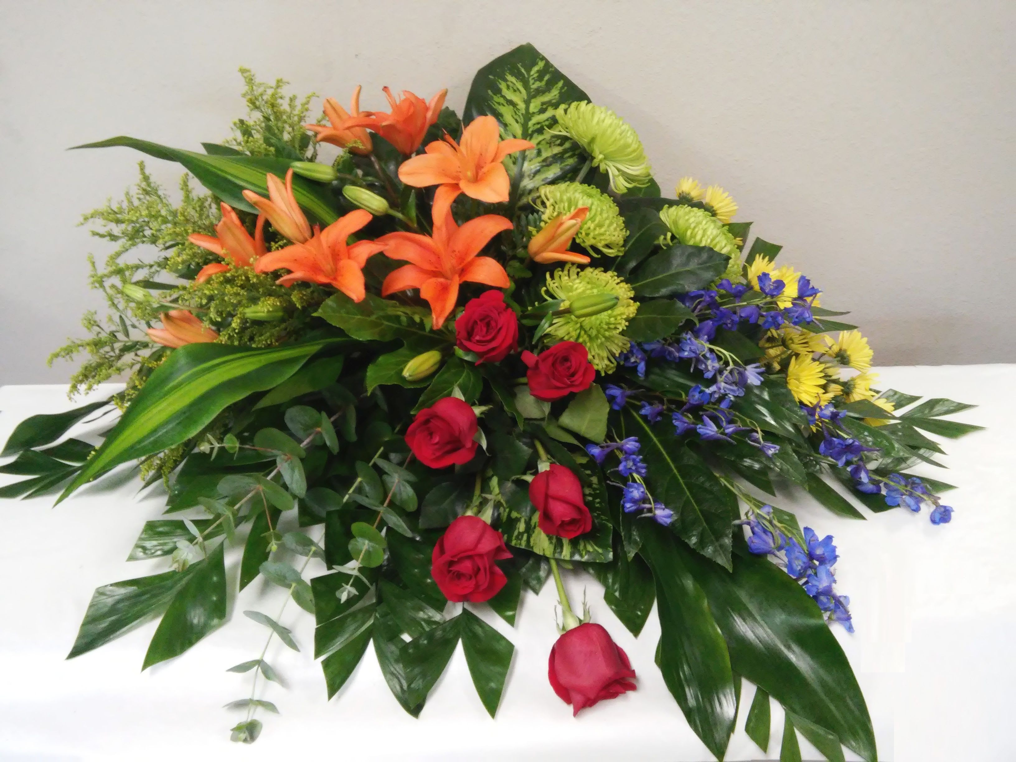 Mixed bouquet with orange lilies, red roses, and blue flowers