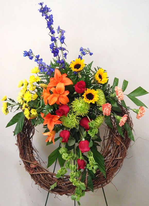 Colorful floral wreath with roses, lilies, sunflowers, and blue delphinium